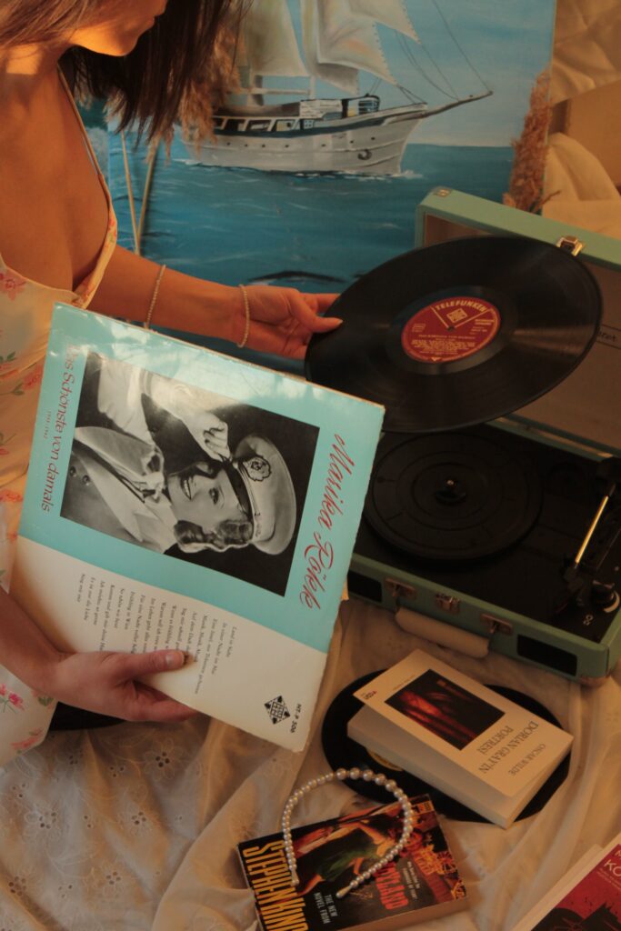 A woman playing a vintage vinyl record on a retro record player, surrounded by books and music albums.