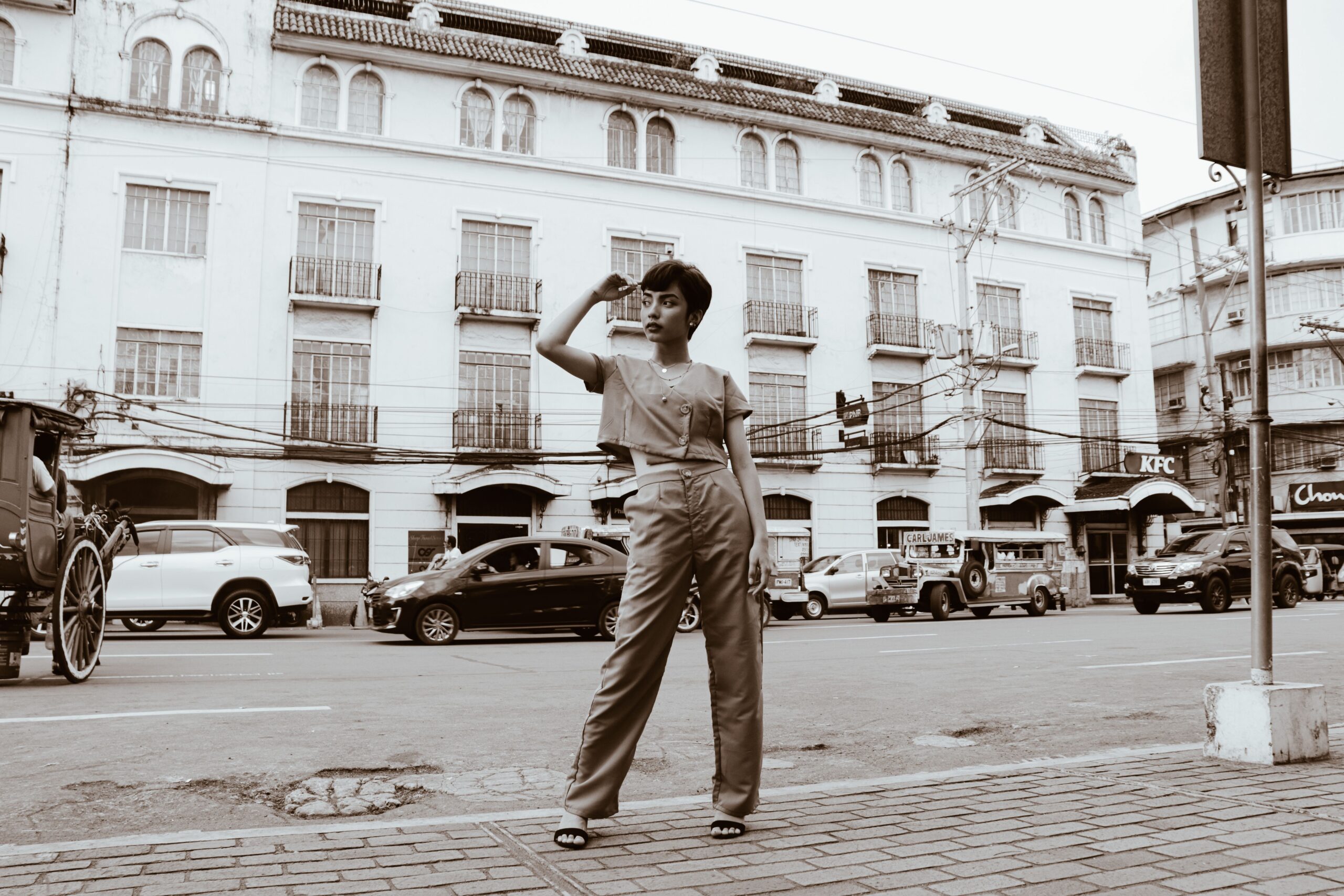 A stylish woman poses on a bustling street in historic Manila. Grayscale adds timelessness.